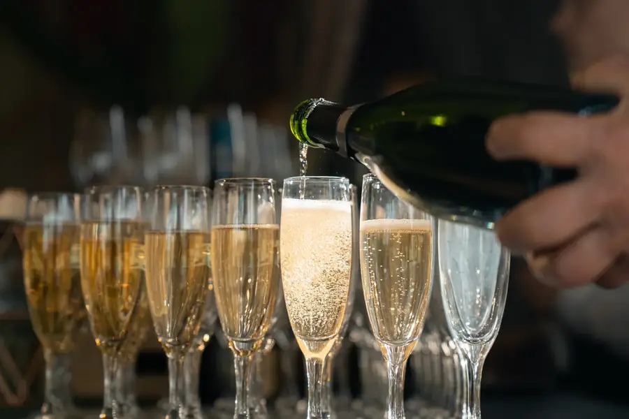 Main versant du champagne dans des flûtes lors d'un événement — Lucas Gouritin