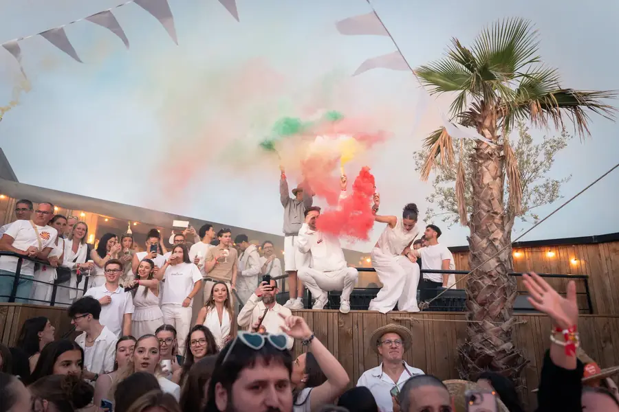 Foule joyeuse avec fumigènes colorés lors d'un événement festif extérieur — Lucas Gouritin