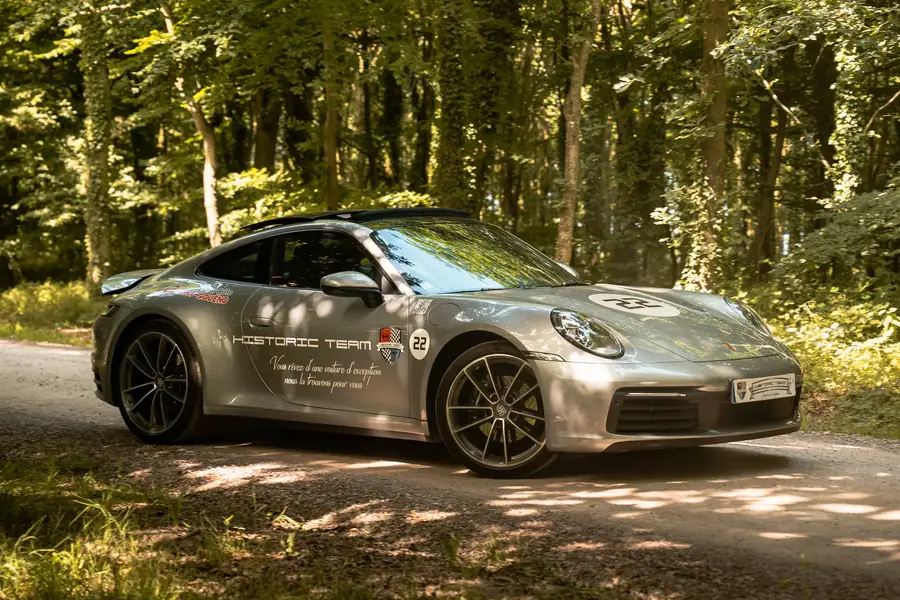 Porsche moderne argentée stationnée en forêt sur chemin de terre — Lucas Gouritin